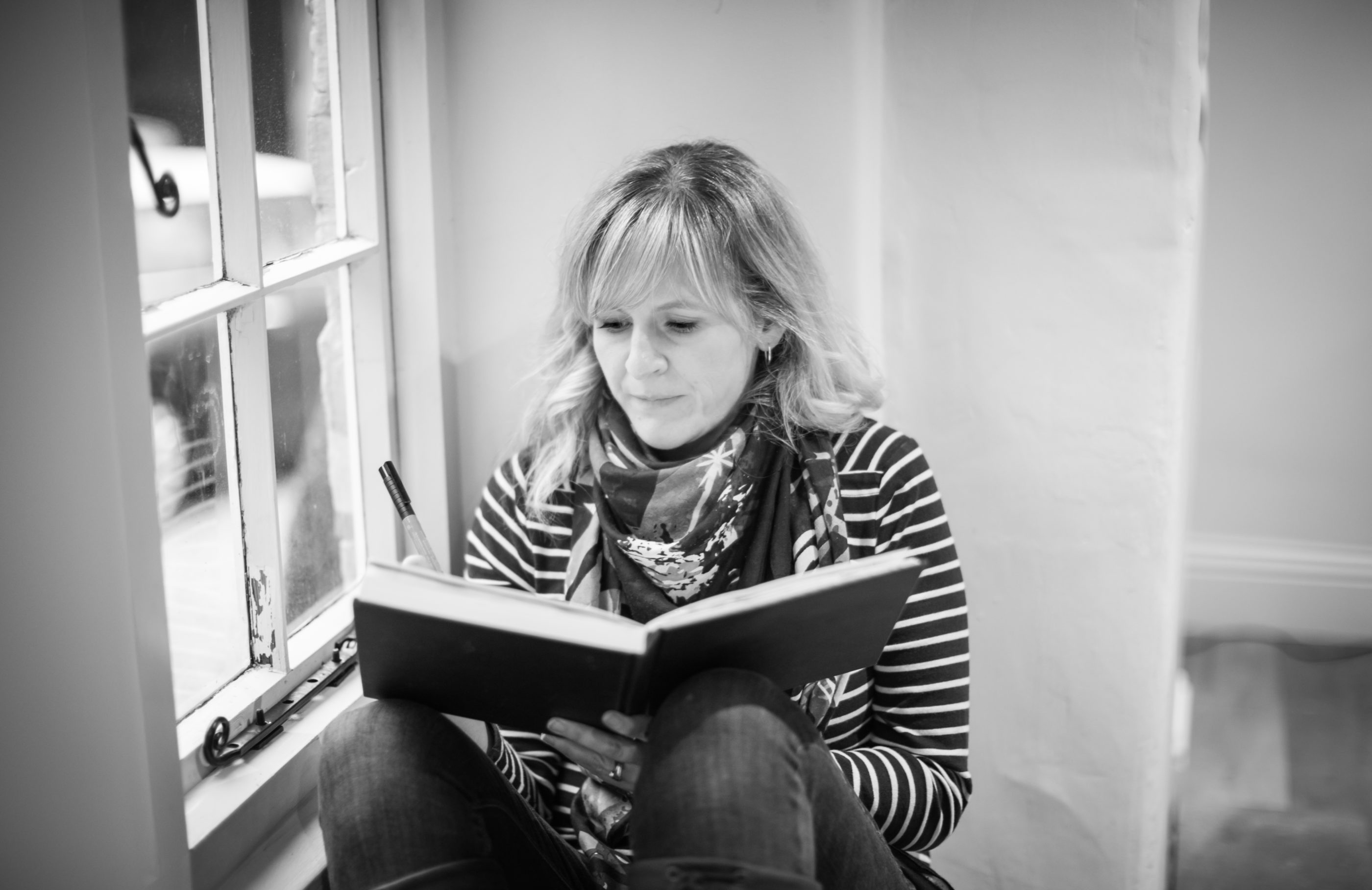Sarah Atkins sitting in a window writing in a notebook